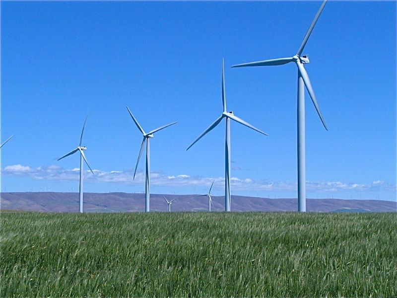 Wind turbines on a green plain under a blue sky